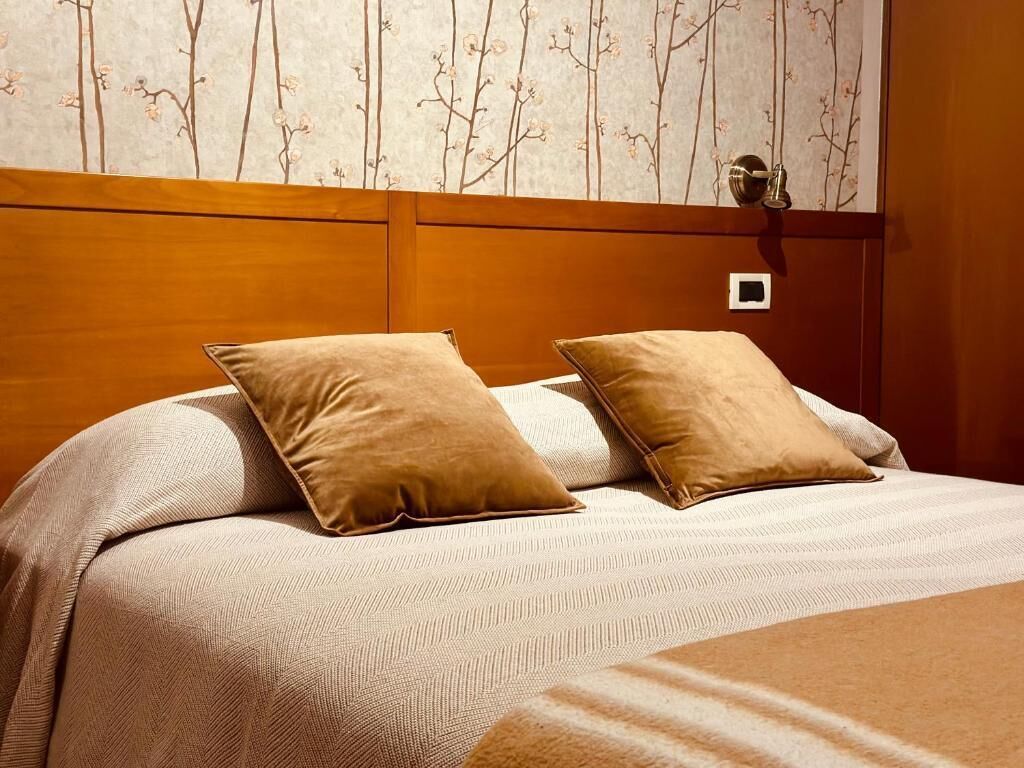 A neatly made bed with two pillows and a striped blanket.