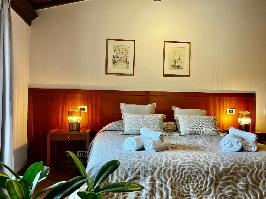 Habitación de hotel con una cama grande, dos lámparas de noche y dos cuadros en la pared.