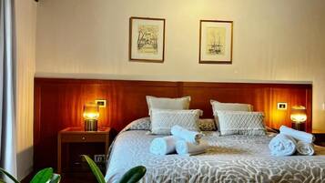 Habitación de hotel con una cama grande, dos lámparas de noche y dos cuadros en la pared.