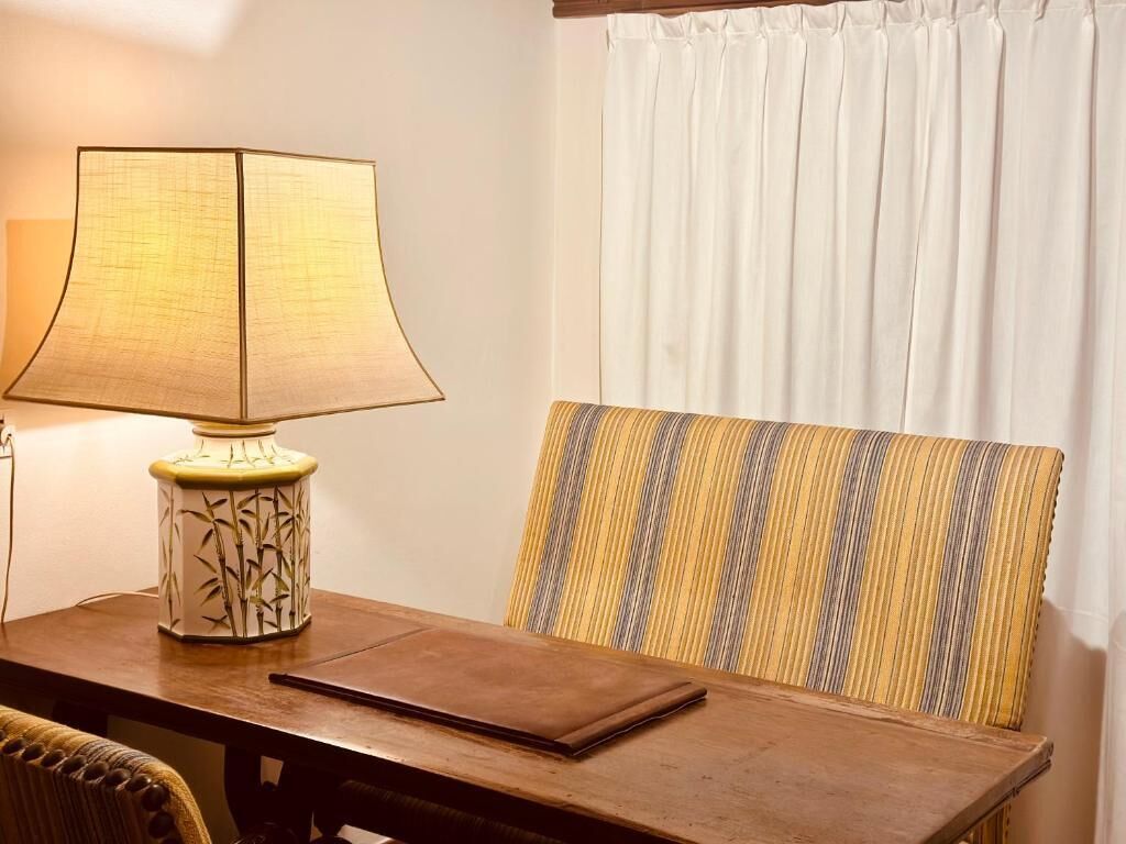 Une table en bois, une lampe et un coussin à rayures.