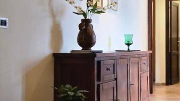 Un pasillo con un mueble de madera, un jarrón con flores y cuadros en la pared.