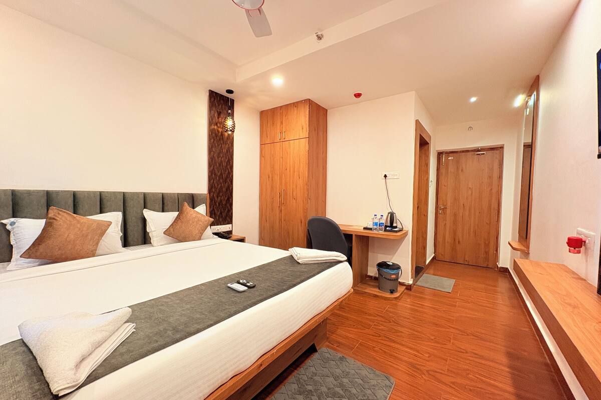 A modern hotel room with a large bed, a desk, and a wardrobe.