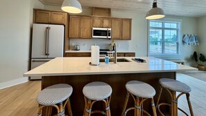 Una cocina moderna con armarios de madera, una isla grande con taburetes de bar, un refrigerador y una ventana con vistas.
