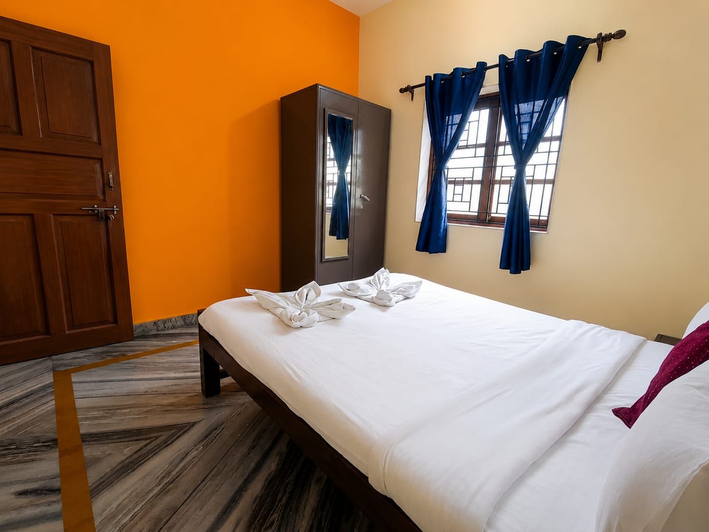 A hotel room with a bed, a wardrobe, and a window with curtains.