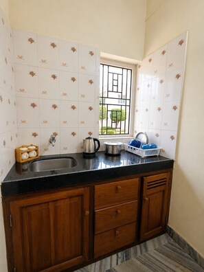 A kitchen with a black countertop, stainless steel sink, and wooden cabinets. - Nunes sea Villa (Candolim)