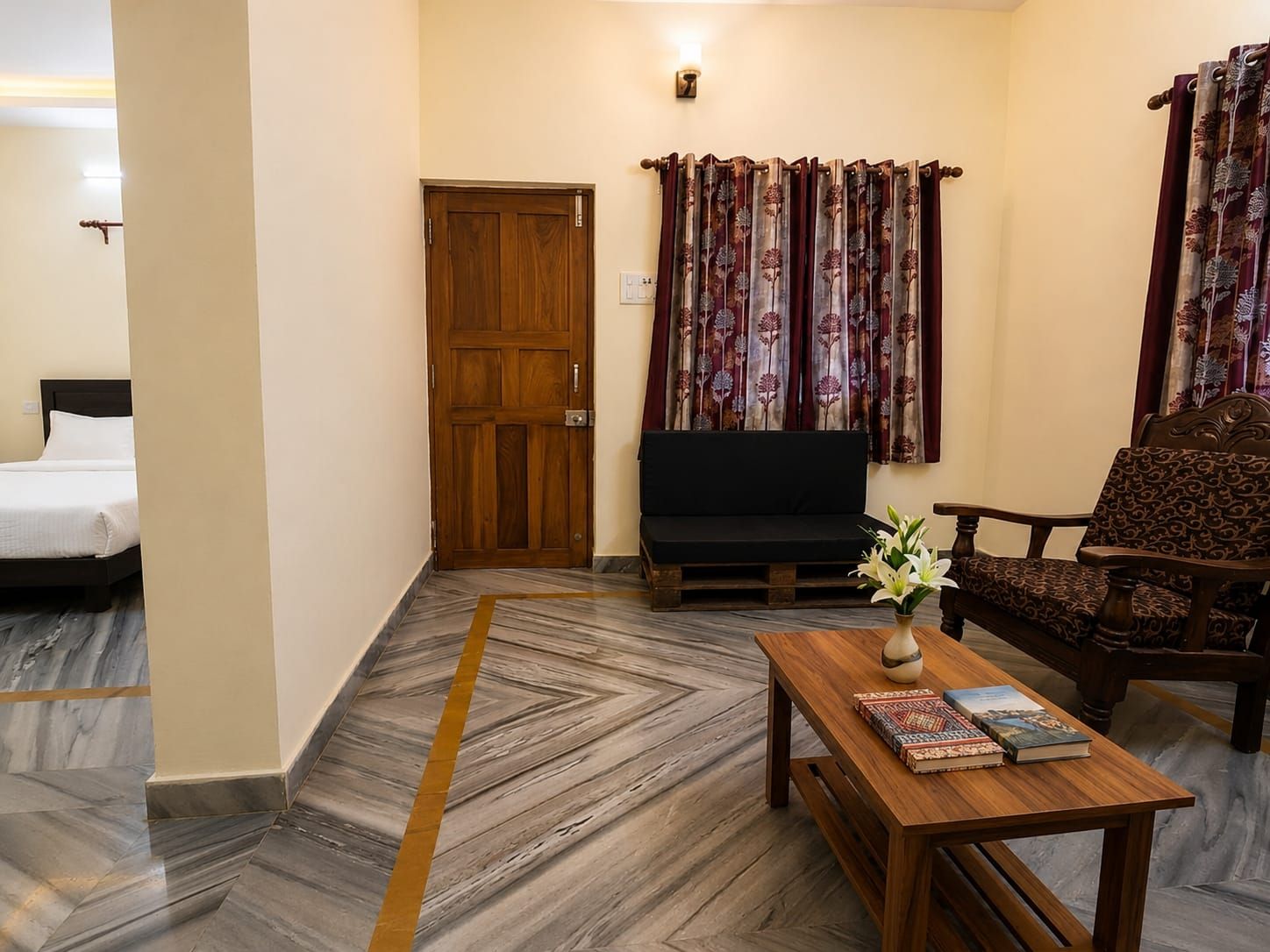 Una habitación de hotel con una cama, un sofá, una mesa de madera con libros y una silla.