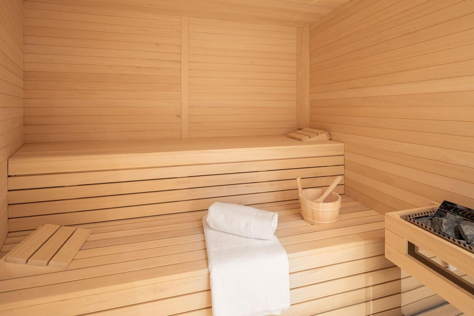 Een sauna met houten banken, een witte handdoek en een houten emmer.