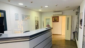 Un espace d’accueil avec un comptoir, des certificats encadrés accrochés au mur et une porte donnant sur une autre pièce.