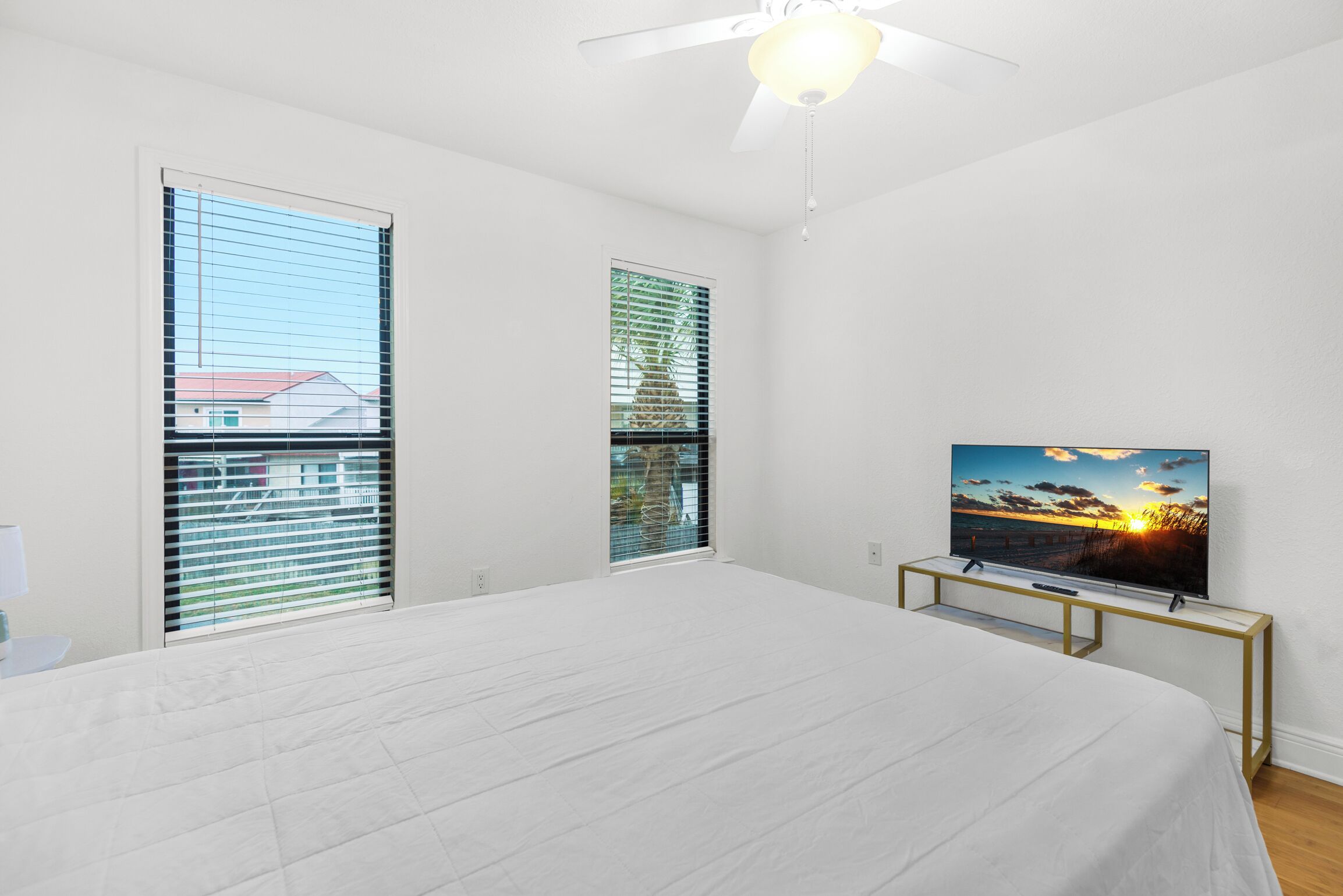 A bedroom with a large bed, a ceiling fan, and a TV on a stand.