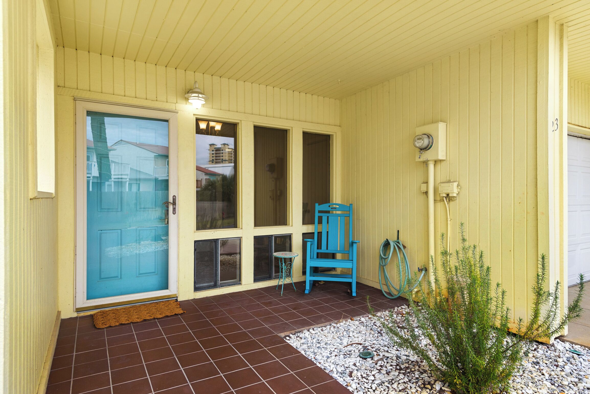 A covered porch with a blue door, a blue chair, and a small table.