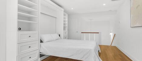 A bedroom with a bed, white wardrobe, and a radiator.