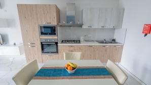 A modern kitchen with wooden cabinets, a gas stove, a microwave, and a sink. - Chic Modern 1BR APT near Salina Bay (St. Paul's Bay)