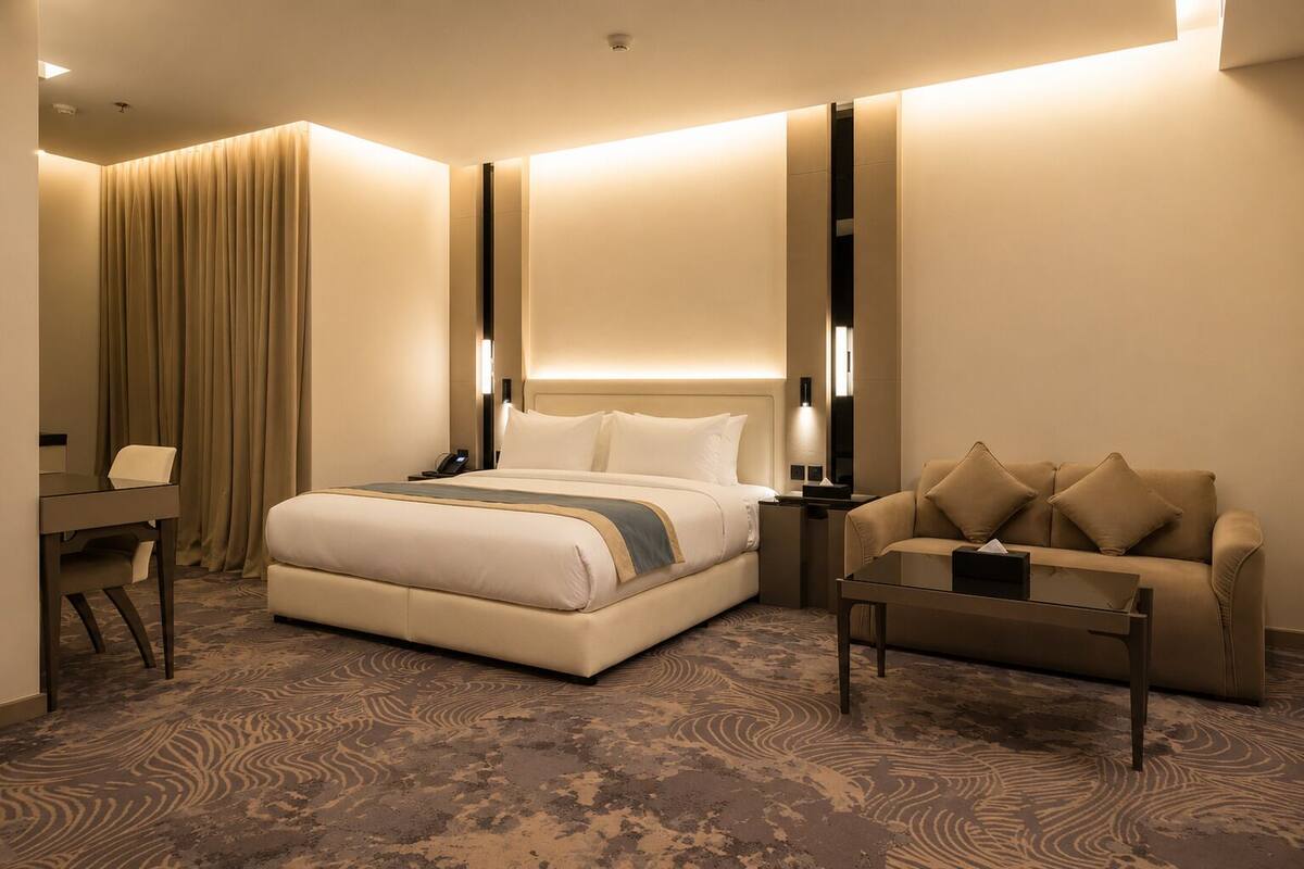 Une chambre d’hôtel avec un grand lit, un bureau, un canapé et une moquette à motifs.