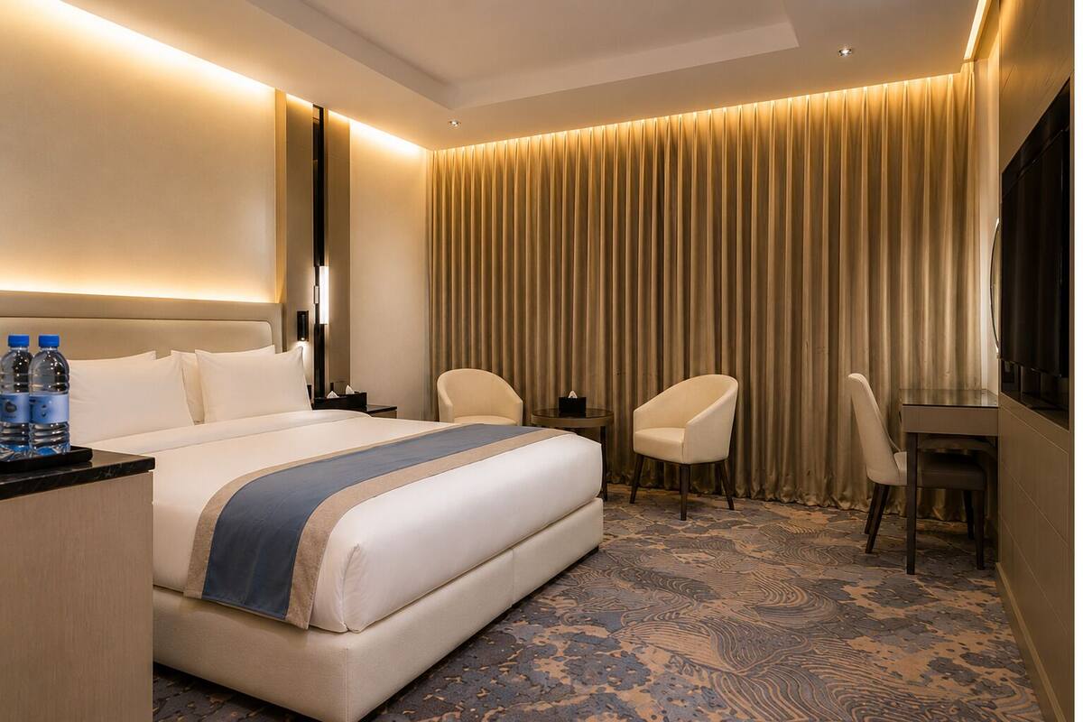 Une chambre d’hôtel avec un lit, deux chaises, un bureau, une télévision et un rideau.
