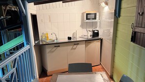 A compact kitchen with a sink, microwave, and countertop. - Bungalow COQUILLAGE (Pointe-Noire)