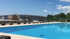 Uma piscina com espreguiçadeiras e vista para a paisagem.