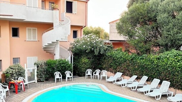 Piscina com espreguiçadeiras e escadaria que dá acesso a um andar superior.