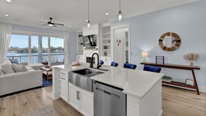 Una cucina moderna con lavastoviglie integrata, un'isola grande e un'area pranzo con sedie blu.
