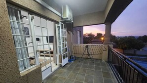 Ein Balkon mit Blick auf den Sonnenuntergang, eine Wäscheständer und ein kleiner Tisch.