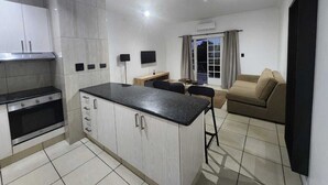 Eine moderne Küche mit einer zentralen Kochinsel, einem eingebauten Backofen und einem Essbereich mit Sofa und Tisch.