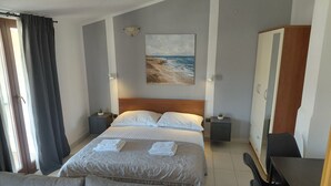 Habitación de hotel con cama, mesitas de noche, escritorio, silla, armario y un cuadro en la pared.