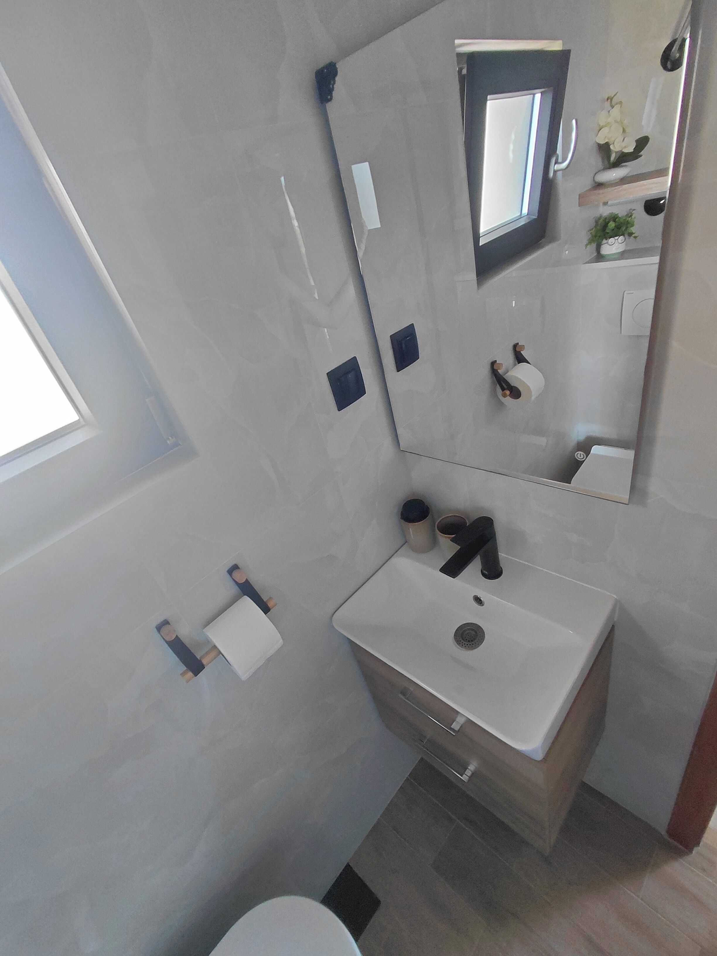 Een moderne badkamer met een witte wastafel, spiegel en toilet.