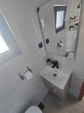 A modern bathroom with a white sink, mirror, and toilet. -  Apartment A2+1 in delightful Grebaštica with AC comfort (Grebaštica)