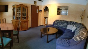 A living room with a blue sofa, a wooden table, a cabinet, and a television mounted on the wall. - Bayerwald Apartment in Arrach (Arrach)