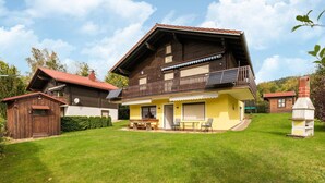 A two-story wooden house with a balcony, a solar panel, and a chimney. - Bayerwald Apartment in Arrach (Arrach)