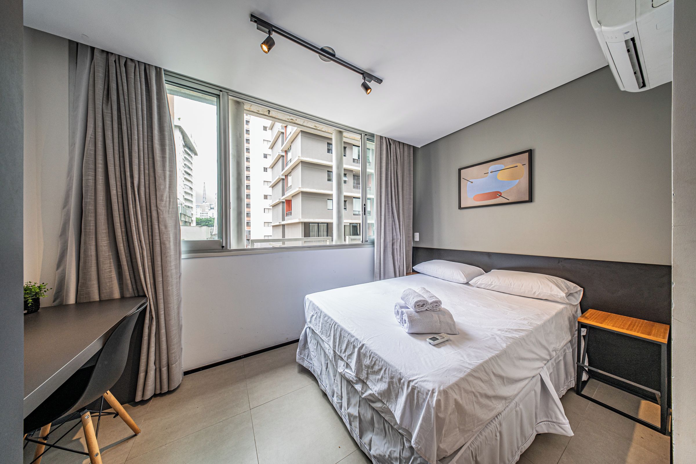Una habitación de hotel con cama, escritorio y ventana con cortinas.