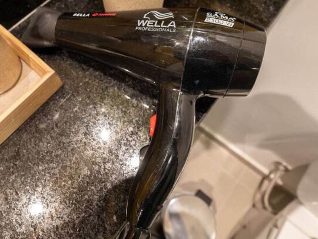 A black WELLA Professionals hair dryer with a 2100 W power rating.