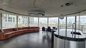 Ett modernt vardagsrum med en böjd form och ett stort fönster med utsikt över stadsbilden.