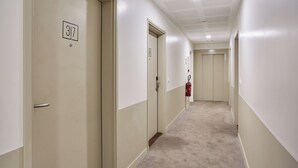A corridor with doors labeled 317 and 38, carpeted flooring, and a fire extinguisher mounted on the wall. - Hôtel Maison Saint Charles (Paris)