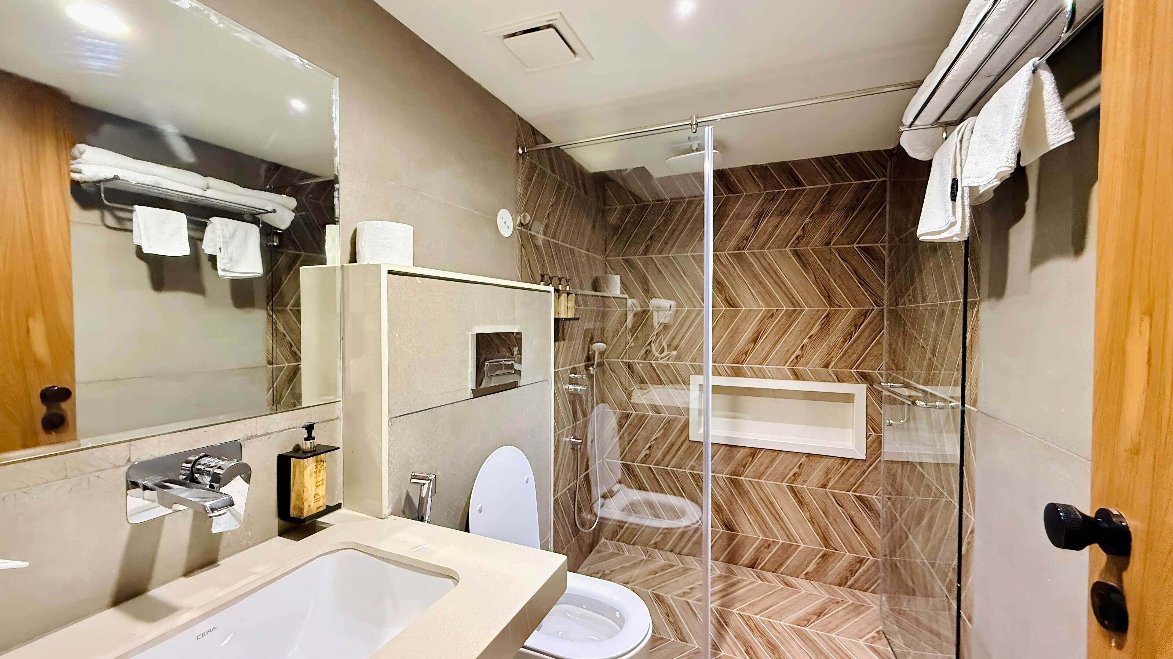 Une salle de bain moderne avec une douche à parois de verre, un lavabo doté d’un distributeur de savon et des toilettes.