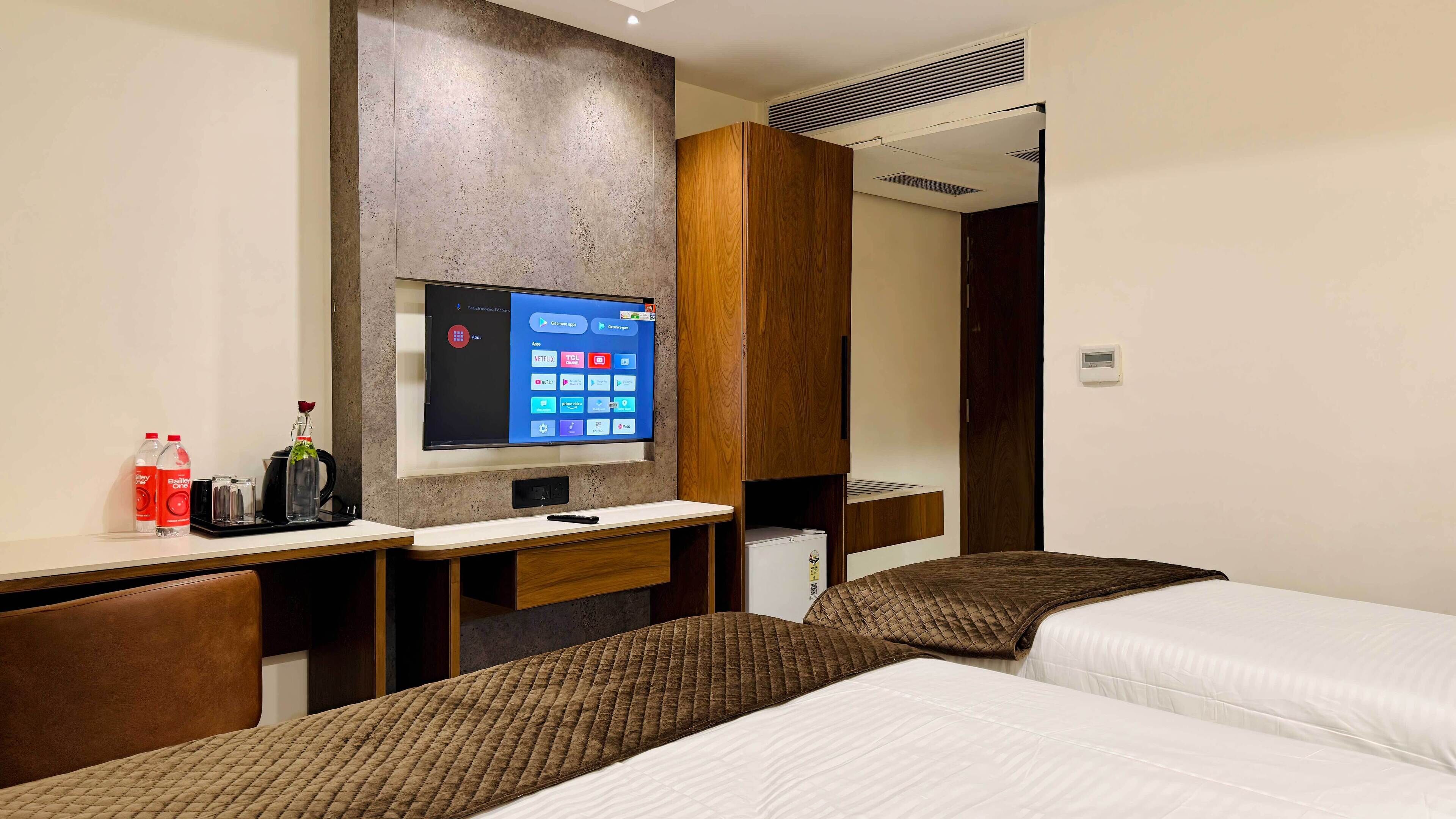 A hotel room with a bed, a desk with a TV, and a minibar.