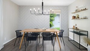 Et moderne spiseområde med et træbord, sorte stole og en sort lysekrone.