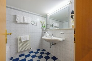 Une salle de bain avec un lavabo blanc, un miroir, un porte-serviettes et un radiateur.