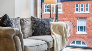 A living room with a sofa, pillows, and a floor lamp. - Long stay | 1-Bed Jewellery Quarter Apt | Homely (Birmingham)