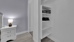 A white dresser with drawers and a lamp, a white closet with shelves, and a grey wall. - Cozy 1-bedroom condo walking distance to Las Vegas strip (Las Vegas)