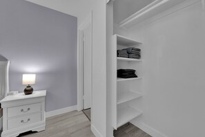 Ein weißer Schminktisch mit Schubladen und einer Lampe, ein weißer Kleiderschrank mit Regalen und eine graue Wand.