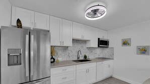 A modern kitchen with white cabinets, a stainless steel refrigerator, a microwave, and a sink. - Cozy 1-bedroom condo walking distance to Las Vegas strip (Las Vegas)