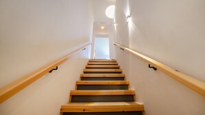Eine Treppe mit Holzboden und Geländern, die zu einer Tür oben führt.