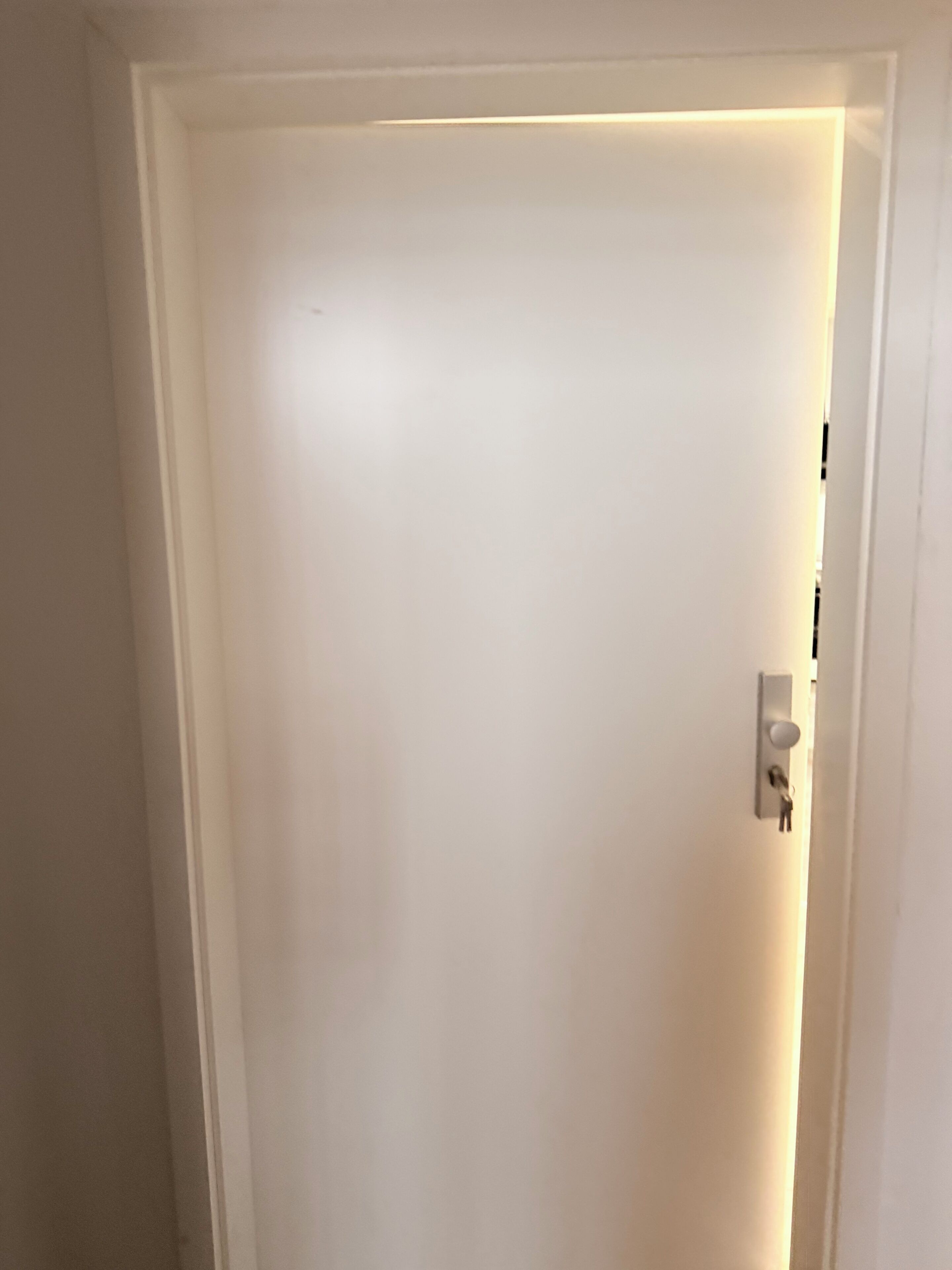 Eine weiße Tür mit Lichtschalter und Schlüsselloch.