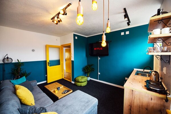 Ein modernes Wohnzimmer mit einer Couch, einem Couchtisch und einem an der Wand befestigten Fernseher.