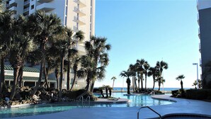 A resort pool area with palm trees and a view of the ocean. - Gulf-Front 1BR w/ Beach Service at Long Beach Resort Tower 3 (Panama City Beach)