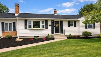 A single-story house with a front porch, a brick chimney, and a black front door.