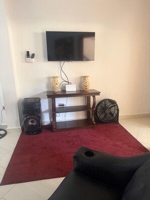 A living room with a TV, two speakers, a fan, and a red carpet. - Spacious family apartment within the Tree Casa resort. Sleeps 8. Pet Friendly. (San Juan del Sur)