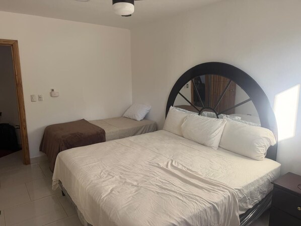 Une chambre avec deux lits, une grande tête de lit circulaire et une porte en bois.