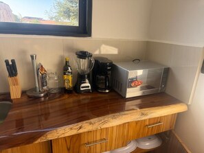 A kitchen with a microwave, coffee maker, blender, and various kitchen utensils.