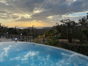 A swimming pool with a view of distant hills and a cloudy sky.